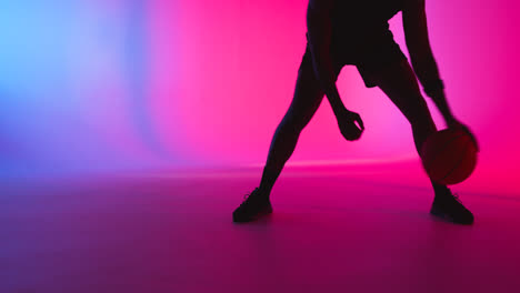 Studio-Silhouette-Of-Male-Basketball-Player-Dribbling-And-Bouncing-Ball-Against-Pink-And-Blue-Lit-Background-1